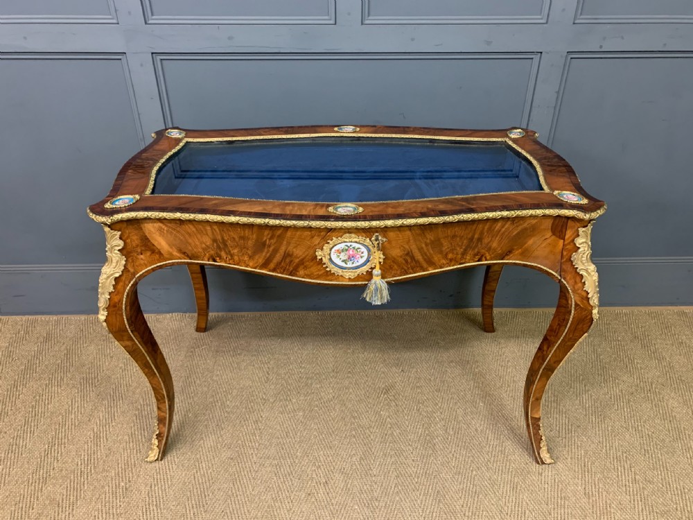 A 19th-century French Louis XV style bijouterie table with a glazed display top, curved cabriole legs, gilt bronze mounts, porcelain plaques, and a blue velvet interior. View II