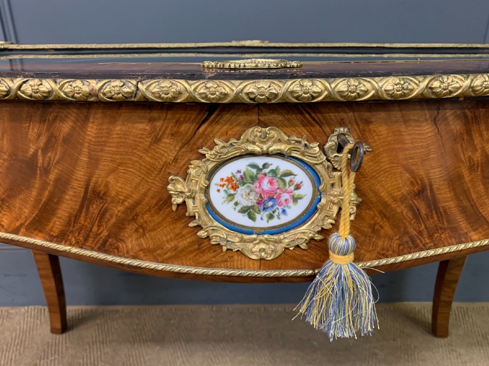 A 19th-century French Louis XV style bijouterie table with a glazed display top, curved cabriole legs, gilt bronze mounts, porcelain plaques, and a blue velvet interior. View VI