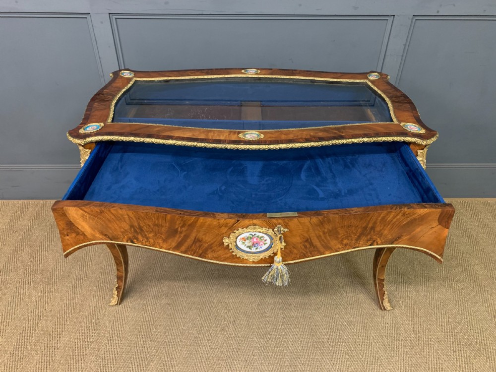 A 19th-century French Louis XV style bijouterie table with a glazed display top, curved cabriole legs, gilt bronze mounts, porcelain plaques, and a blue velvet interior. View VIII
