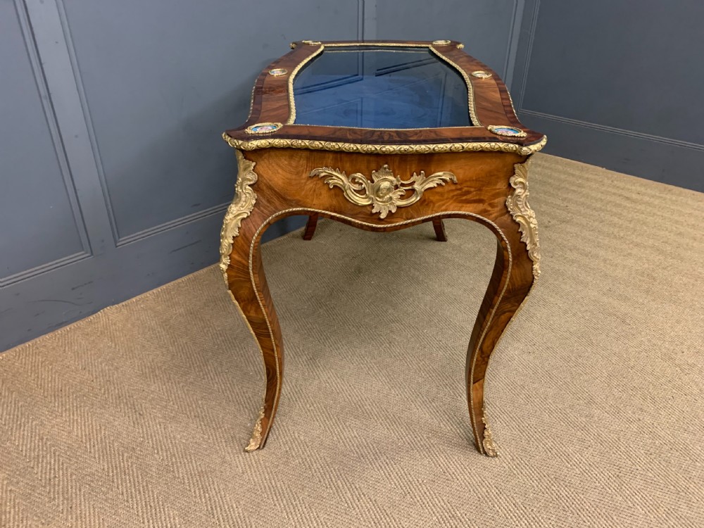 A 19th-century French Louis XV style bijouterie table with a glazed display top, curved cabriole legs, gilt bronze mounts, porcelain plaques, and a blue velvet interior. View IX