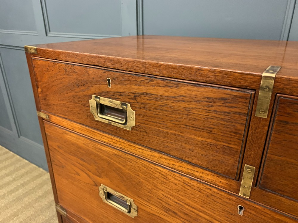 A Victorian teak two-part military campaign chest featuring flush brass handles, brass corner brackets, and turned legs. View V