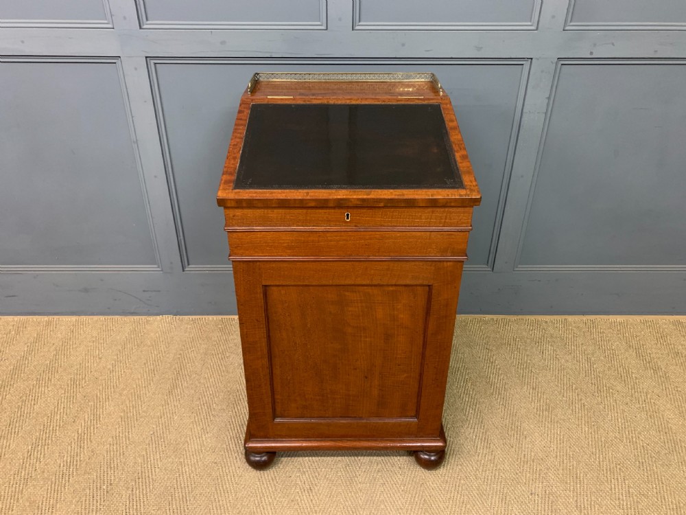 A George IV mahogany Davenport desk featuring a slanted brown leather writing surface, brass gallery rail, four side drawers with turned knobs, and bun feet. View III