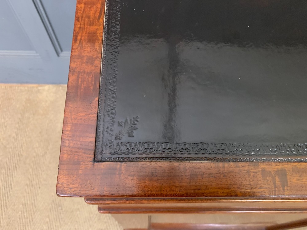 A George IV mahogany Davenport desk featuring a slanted brown leather writing surface, brass gallery rail, four side drawers with turned knobs, and bun feet. View VII