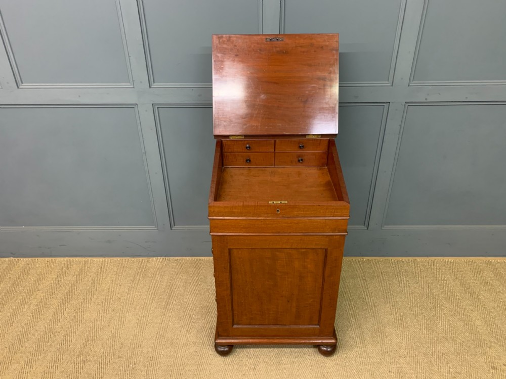 A George IV mahogany Davenport desk featuring a slanted brown leather writing surface, brass gallery rail, four side drawers with turned knobs, and bun feet. View VIII