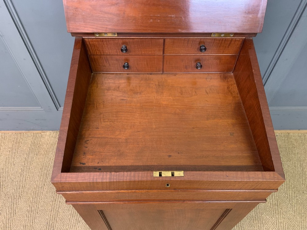 A George IV mahogany Davenport desk featuring a slanted brown leather writing surface, brass gallery rail, four side drawers with turned knobs, and bun feet. View IX