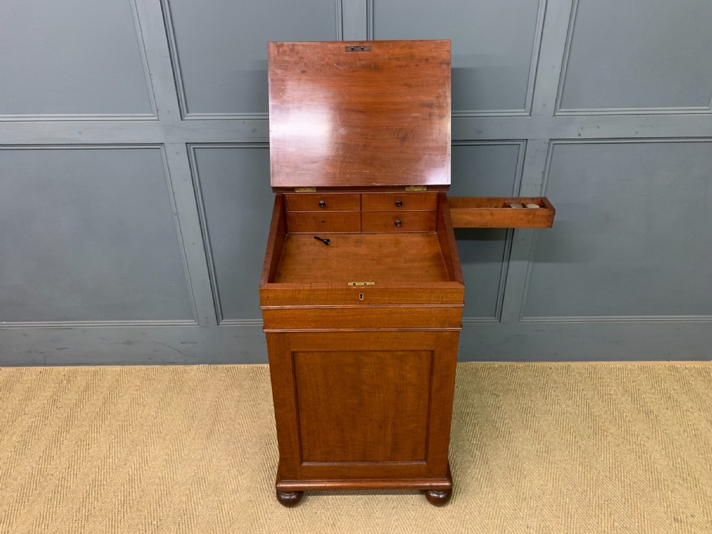 A George IV mahogany Davenport desk featuring a slanted brown leather writing surface, brass gallery rail, four side drawers with turned knobs, and bun feet. View XII