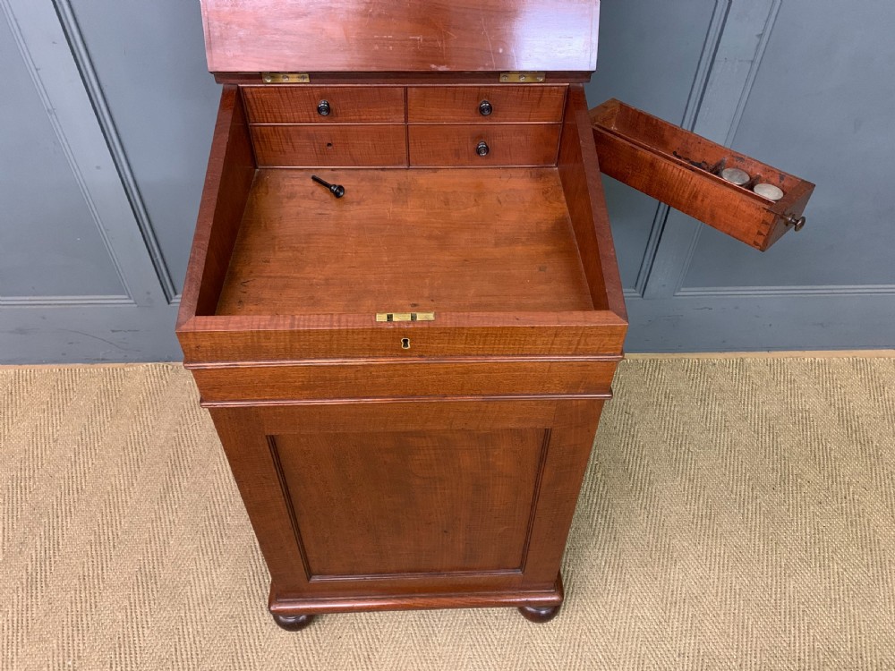 A George IV mahogany Davenport desk featuring a slanted brown leather writing surface, brass gallery rail, four side drawers with turned knobs, and bun feet. View XIII