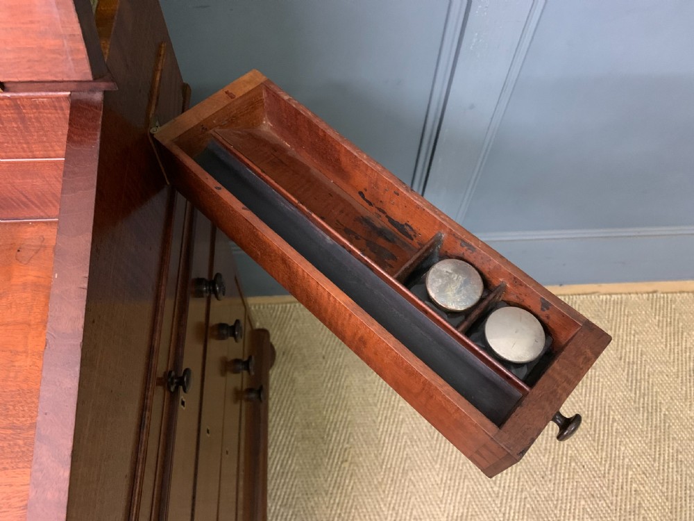A George IV mahogany Davenport desk featuring a slanted brown leather writing surface, brass gallery rail, four side drawers with turned knobs, and bun feet. View XIV