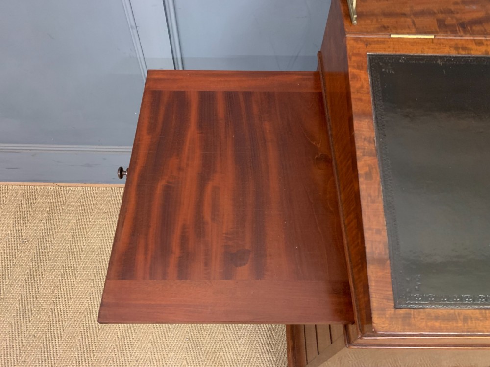 A George IV mahogany Davenport desk featuring a slanted brown leather writing surface, brass gallery rail, four side drawers with turned knobs, and bun feet. View XVII