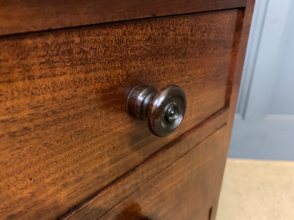 A George IV mahogany Davenport desk featuring a slanted brown leather writing surface, brass gallery rail, four side drawers with turned knobs, and bun feet. View XXI