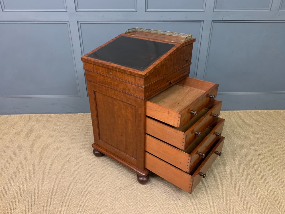 A George IV mahogany Davenport desk featuring a slanted brown leather writing surface, brass gallery rail, four side drawers with turned knobs, and bun feet. View XXII