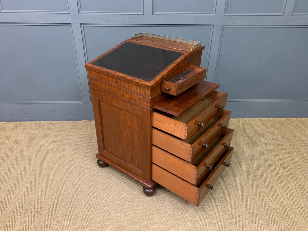 A George IV mahogany Davenport desk featuring a slanted brown leather writing surface, brass gallery rail, four side drawers with turned knobs, and bun feet. View XXIII