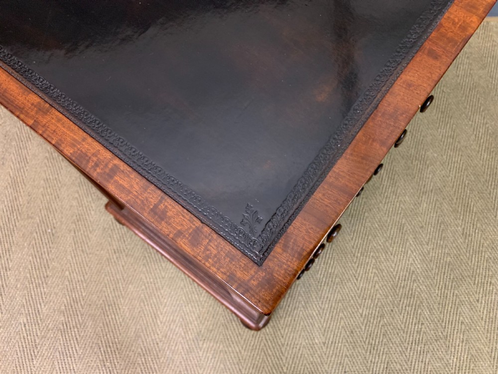 A George IV mahogany Davenport desk featuring a slanted brown leather writing surface, brass gallery rail, four side drawers with turned knobs, and bun feet. View XXIV