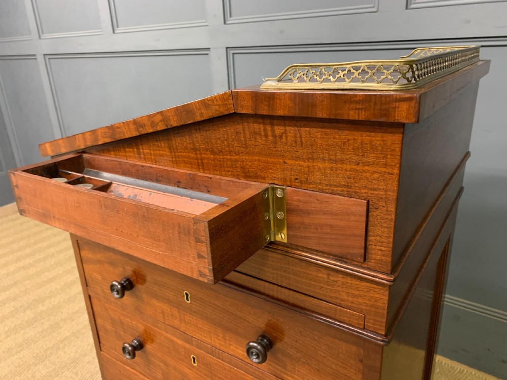 A George IV mahogany Davenport desk featuring a slanted brown leather writing surface, brass gallery rail, four side drawers with turned knobs, and bun feet. View XXV