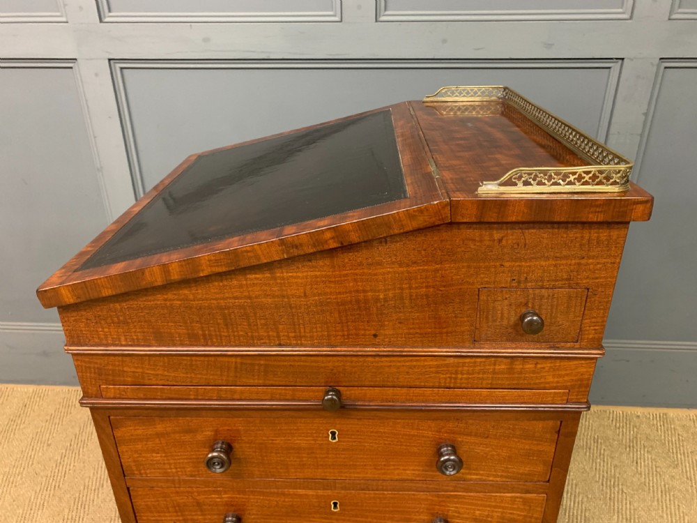 A George IV mahogany Davenport desk featuring a slanted brown leather writing surface, brass gallery rail, four side drawers with turned knobs, and bun feet. View XXVI
