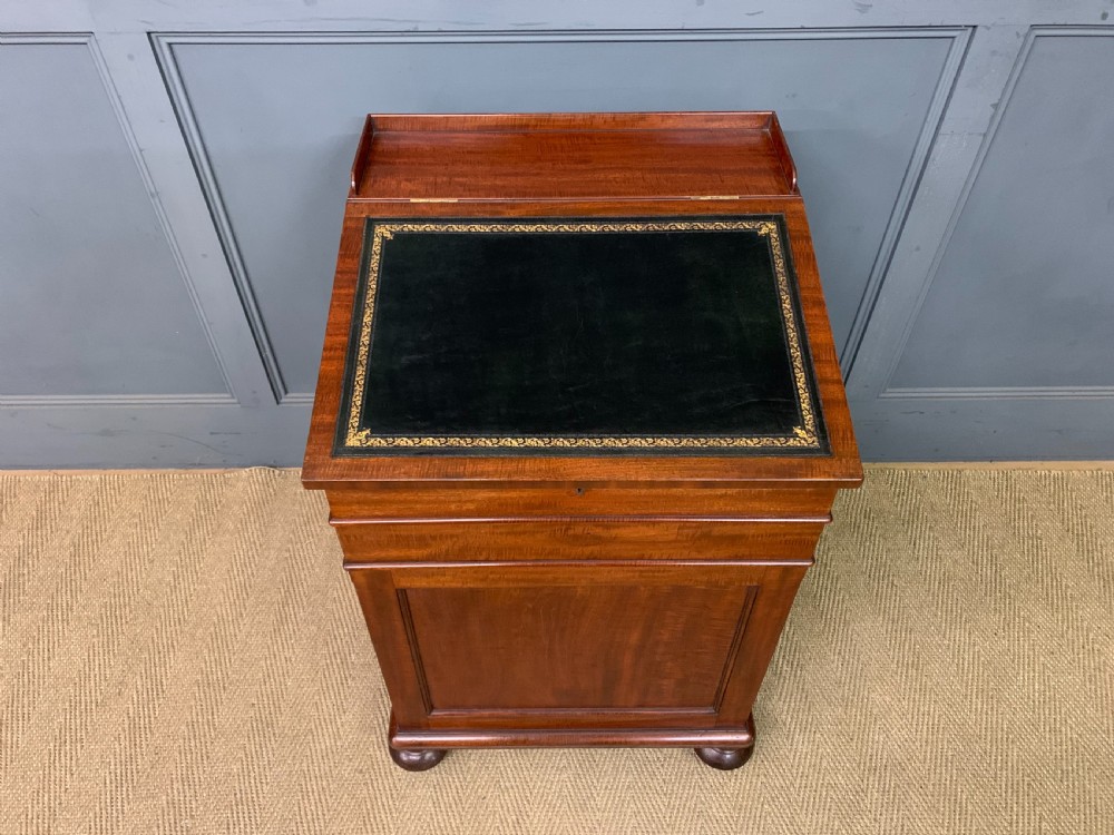 An early Victorian mahogany Davenport desk with a sloped leather writing surface and side drawers. View IV