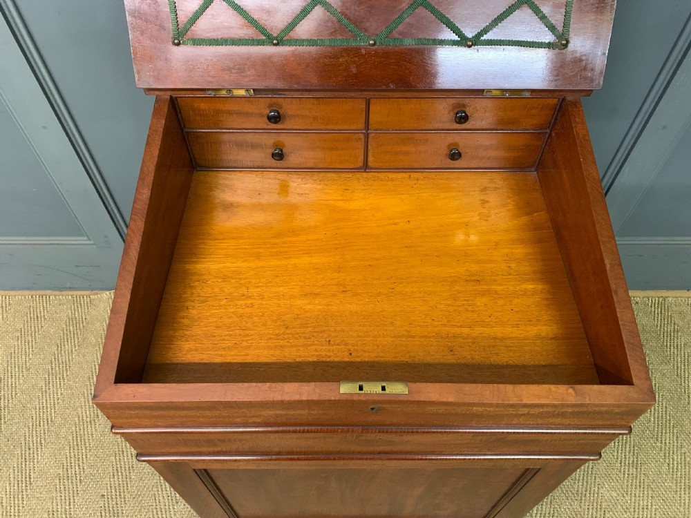 An early Victorian mahogany Davenport desk with a sloped leather writing surface and side drawers. View IX