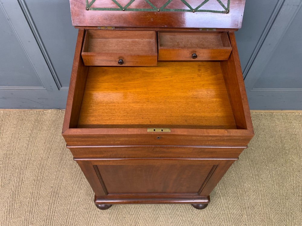 An early Victorian mahogany Davenport desk with a sloped leather writing surface and side drawers. View X