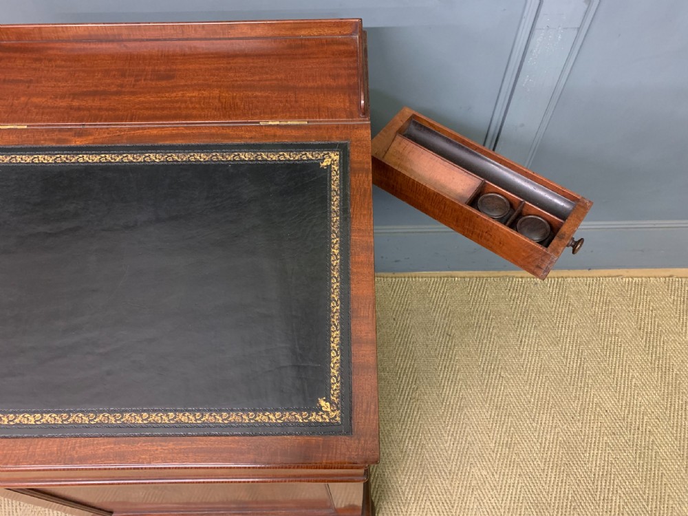 An early Victorian mahogany Davenport desk with a sloped leather writing surface and side drawers. View XIV