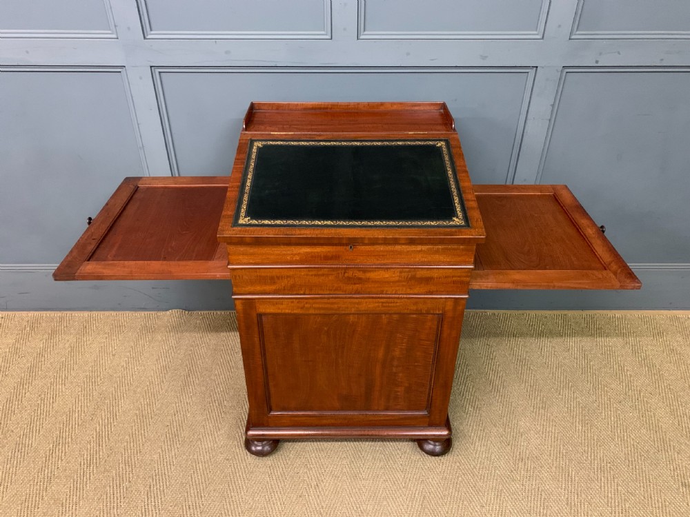 An early Victorian mahogany Davenport desk with a sloped leather writing surface and side drawers. View XVI