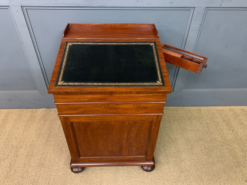 An early Victorian mahogany Davenport desk with a sloped leather writing surface and side drawers. View XVII