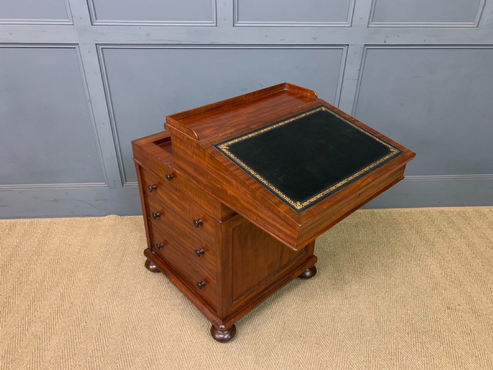An early Victorian mahogany Davenport desk with a sloped leather writing surface and side drawers. View XIX