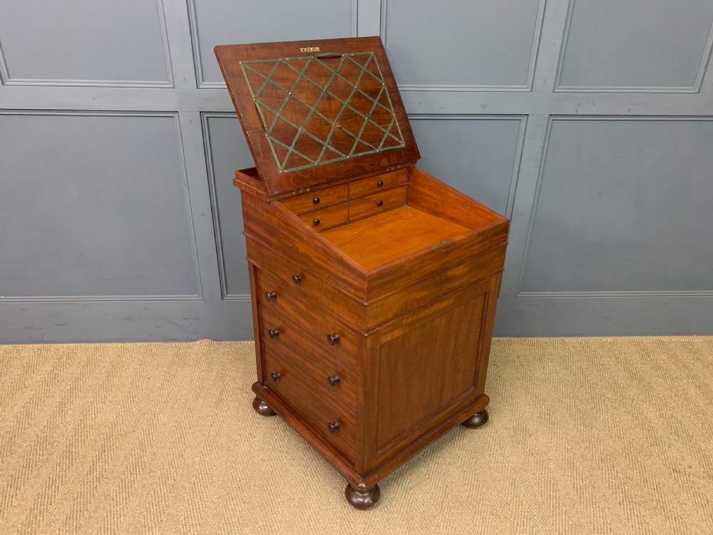 An early Victorian mahogany Davenport desk with a sloped leather writing surface and side drawers. View XX