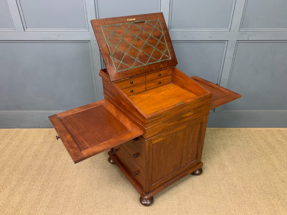 An early Victorian mahogany Davenport desk with a sloped leather writing surface and side drawers. View XXIV
