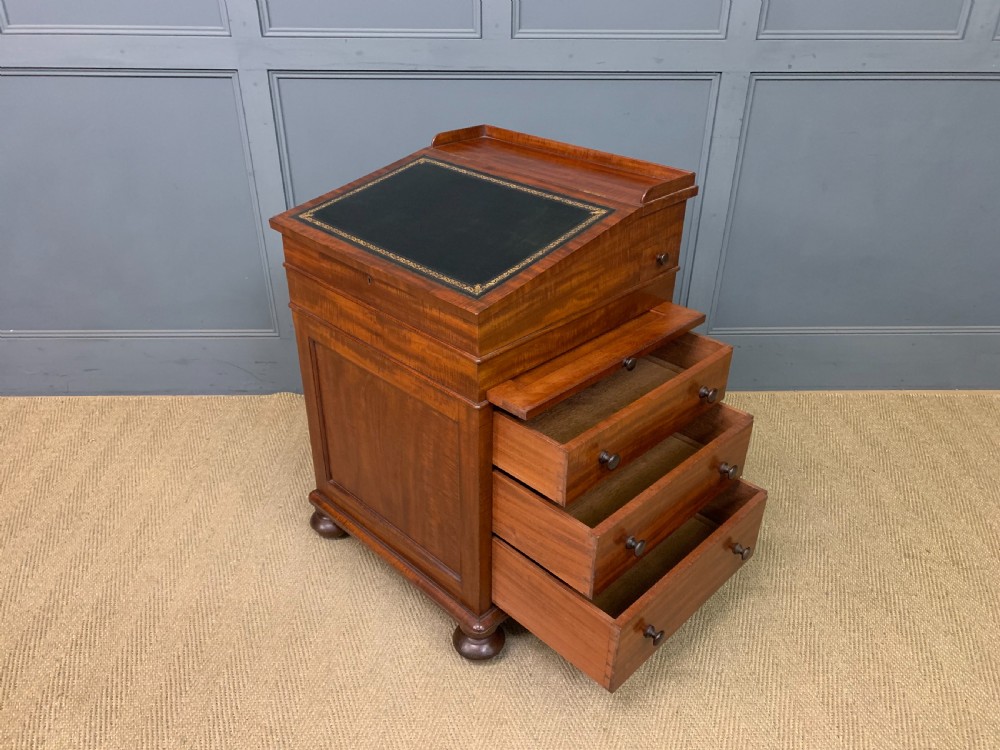 An early Victorian mahogany Davenport desk with a sloped leather writing surface and side drawers. View XXV