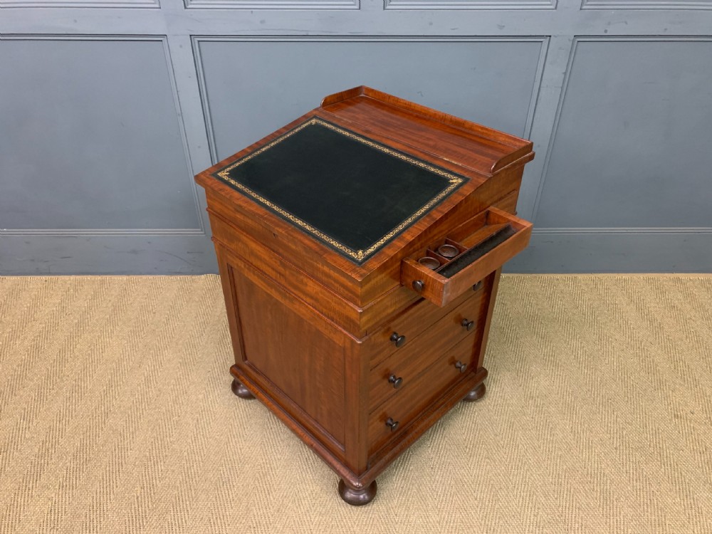 An early Victorian mahogany Davenport desk with a sloped leather writing surface and side drawers. View XXVII