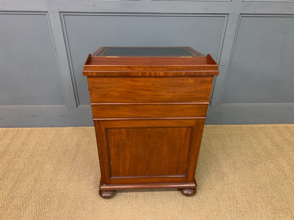 An early Victorian mahogany Davenport desk with a sloped leather writing surface and side drawers. View XXX