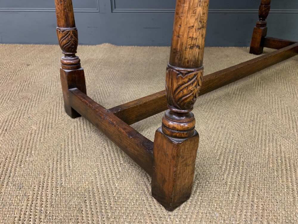 A carved oak dressing table featuring a central tri-fold mirror, three carved drawers, turned legs, and an accompanying stool upholstered in purple patterned fabric. View XV