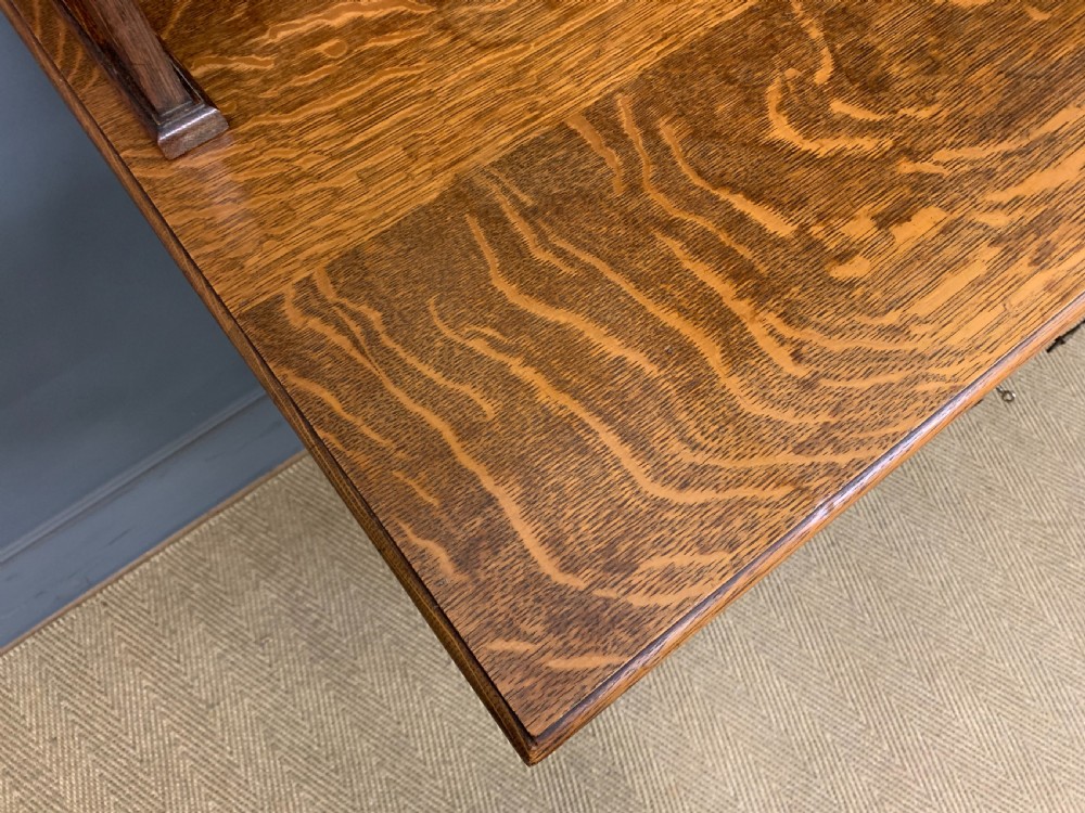 An Arts and Crafts oak sideboard featuring detailed inlaid floral marquetry panels, a central leaded glass upper cabinet, and decorative copper hardware. View XVIII