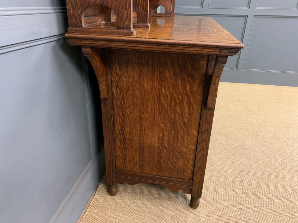 An Arts and Crafts oak sideboard featuring detailed inlaid floral marquetry panels, a central leaded glass upper cabinet, and decorative copper hardware. View XX