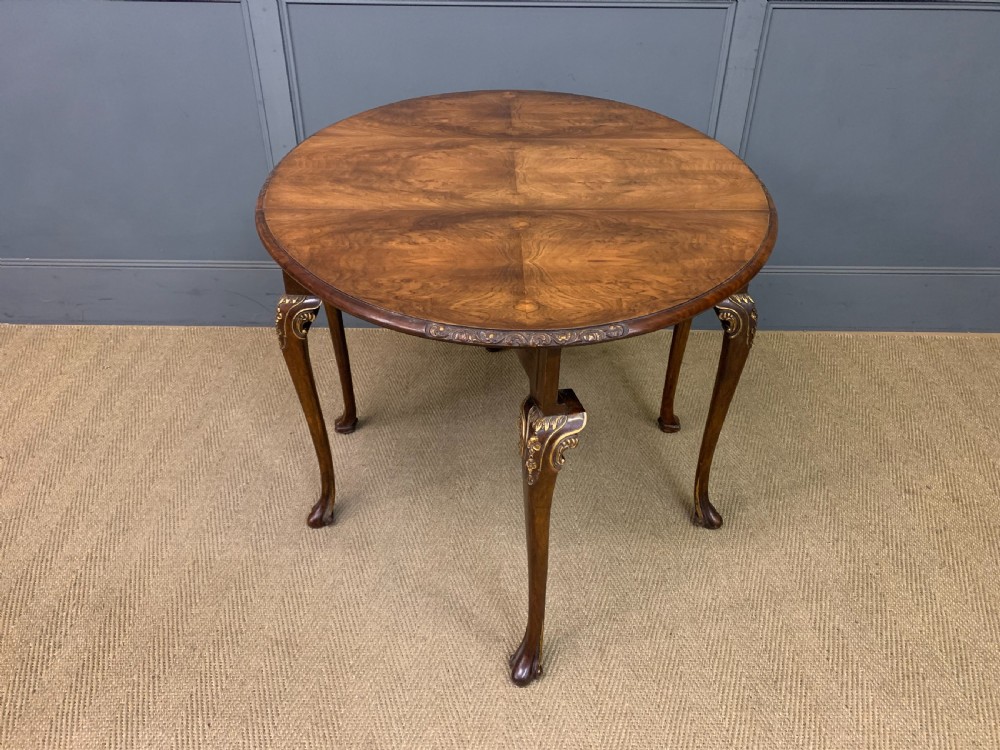A burr walnut drop flap table featuring carved cabriole legs with leaf decoration, a single drawer with brass pull, and two rounded drop leaves. View XII