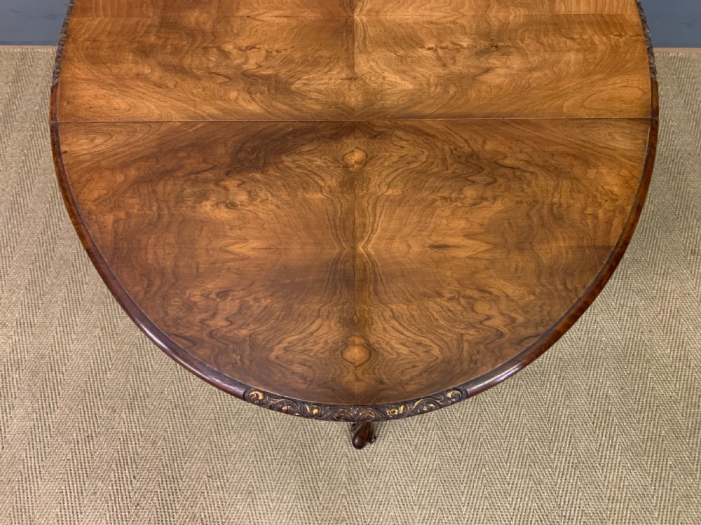 A burr walnut drop flap table featuring carved cabriole legs with leaf decoration, a single drawer with brass pull, and two rounded drop leaves. View XIII