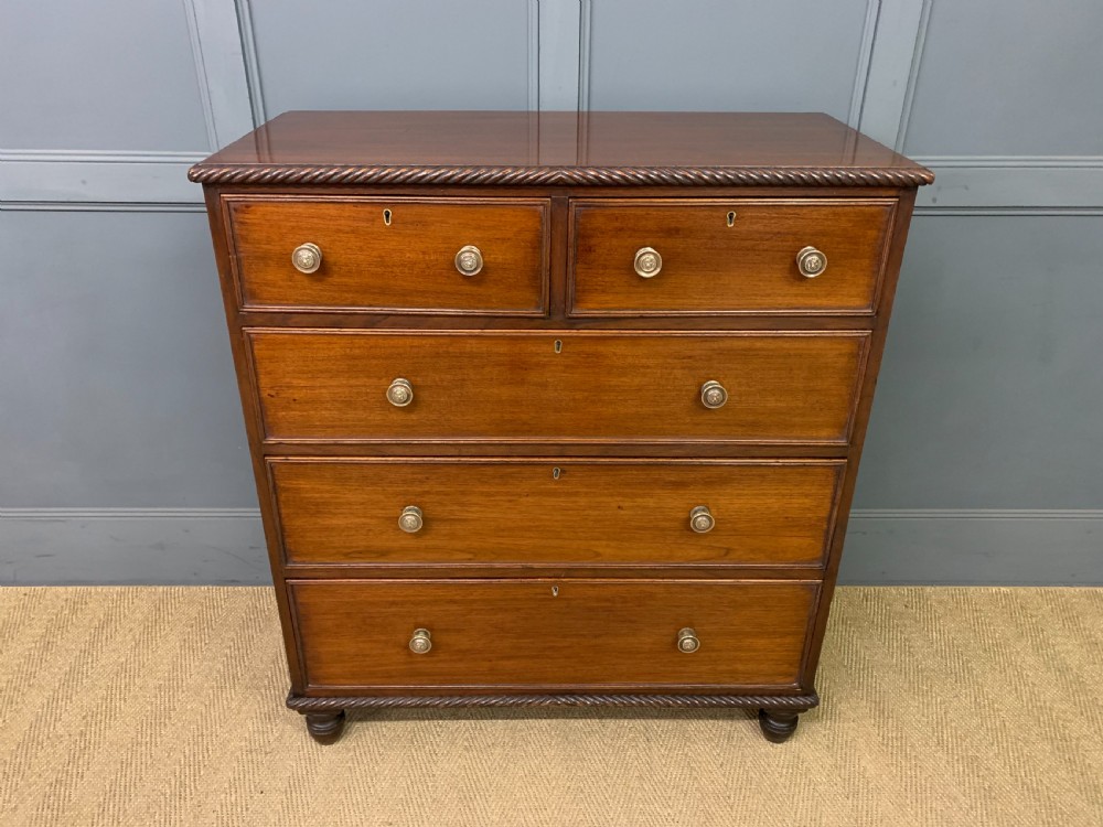 A George IV mahogany chest of drawers featuring two short over three long drawers with turned knobs, brass escutcheons, and rope-twist edge moulding.