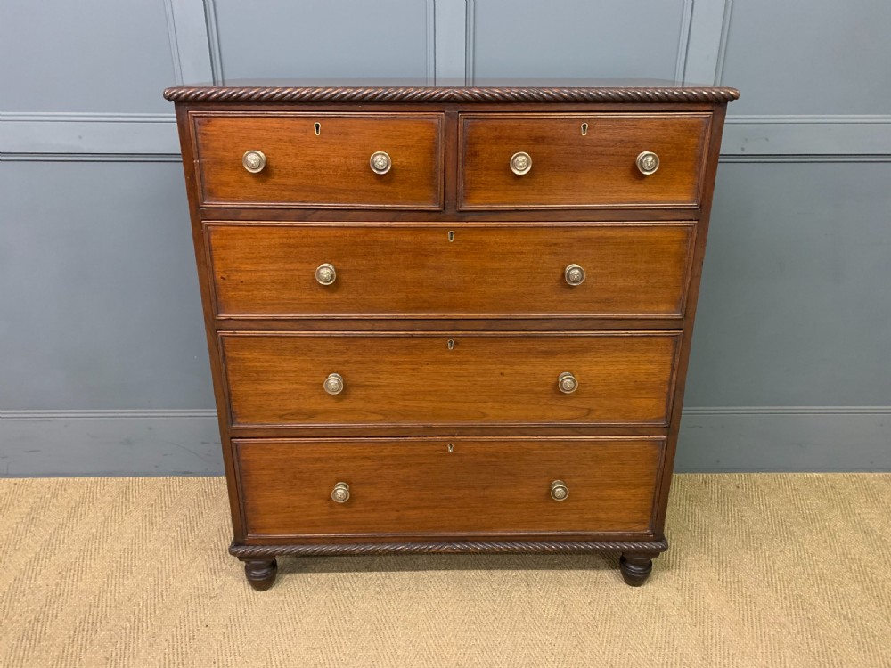 A George IV mahogany chest of drawers featuring two short over three long drawers with turned knobs, brass escutcheons, and rope-twist edge moulding. View II