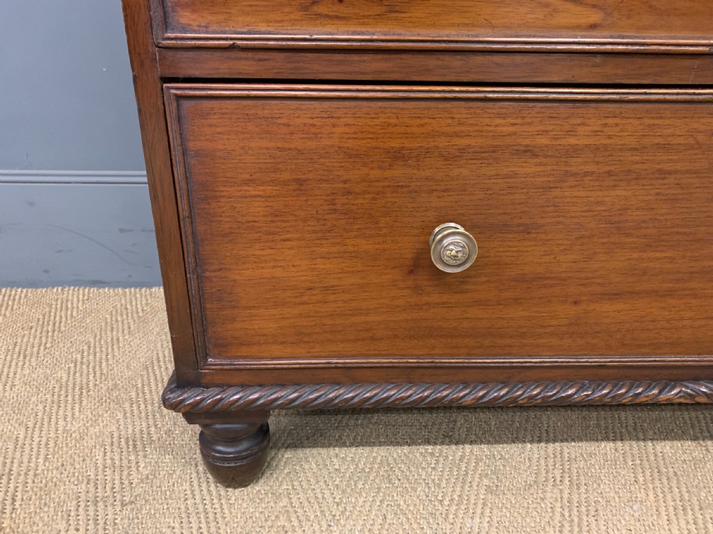A George IV mahogany chest of drawers featuring two short over three long drawers with turned knobs, brass escutcheons, and rope-twist edge moulding. View V
