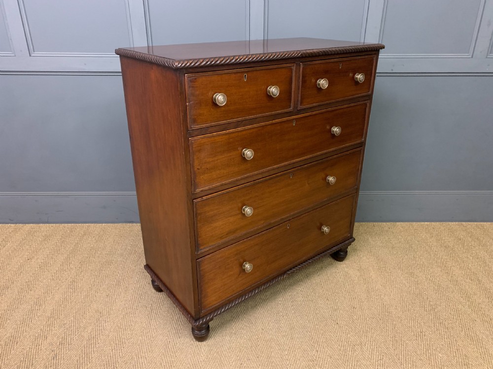 A George IV mahogany chest of drawers featuring two short over three long drawers with turned knobs, brass escutcheons, and rope-twist edge moulding. View VII