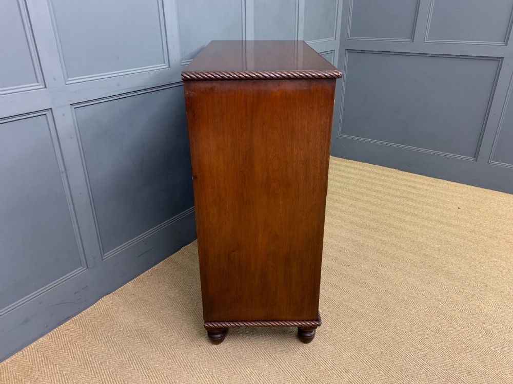 A George IV mahogany chest of drawers featuring two short over three long drawers with turned knobs, brass escutcheons, and rope-twist edge moulding. View VIII