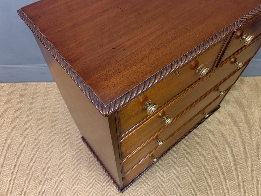 A George IV mahogany chest of drawers featuring two short over three long drawers with turned knobs, brass escutcheons, and rope-twist edge moulding. View X