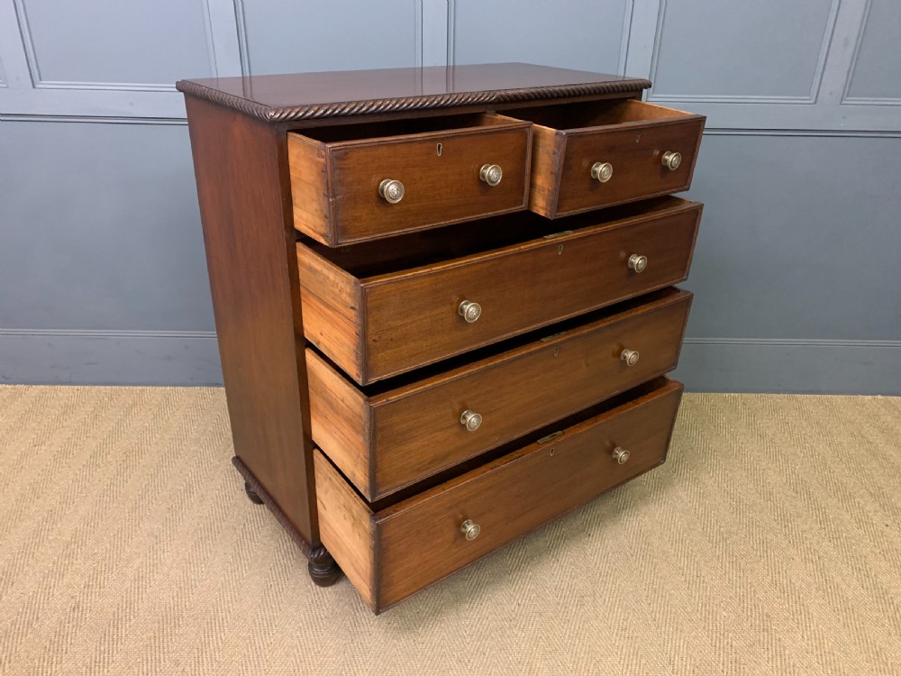 A George IV mahogany chest of drawers featuring two short over three long drawers with turned knobs, brass escutcheons, and rope-twist edge moulding. View XI