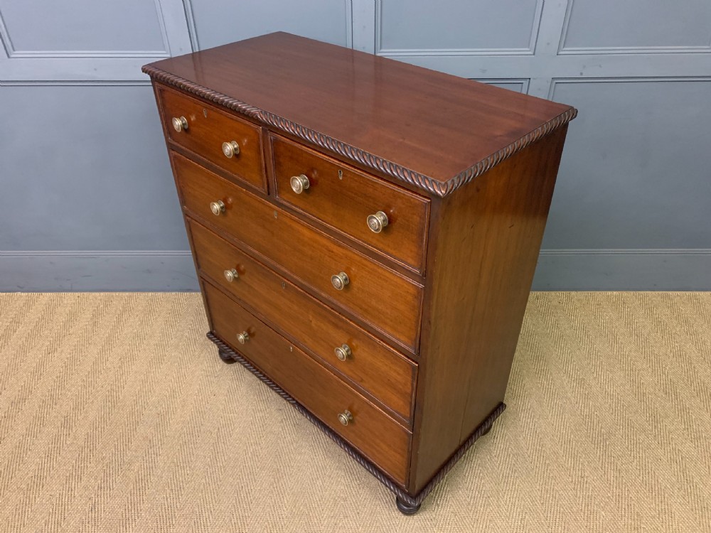 A George IV mahogany chest of drawers featuring two short over three long drawers with turned knobs, brass escutcheons, and rope-twist edge moulding. View XII