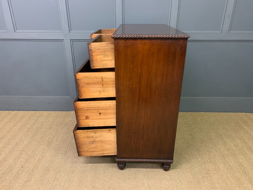 A George IV mahogany chest of drawers featuring two short over three long drawers with turned knobs, brass escutcheons, and rope-twist edge moulding. View XIII