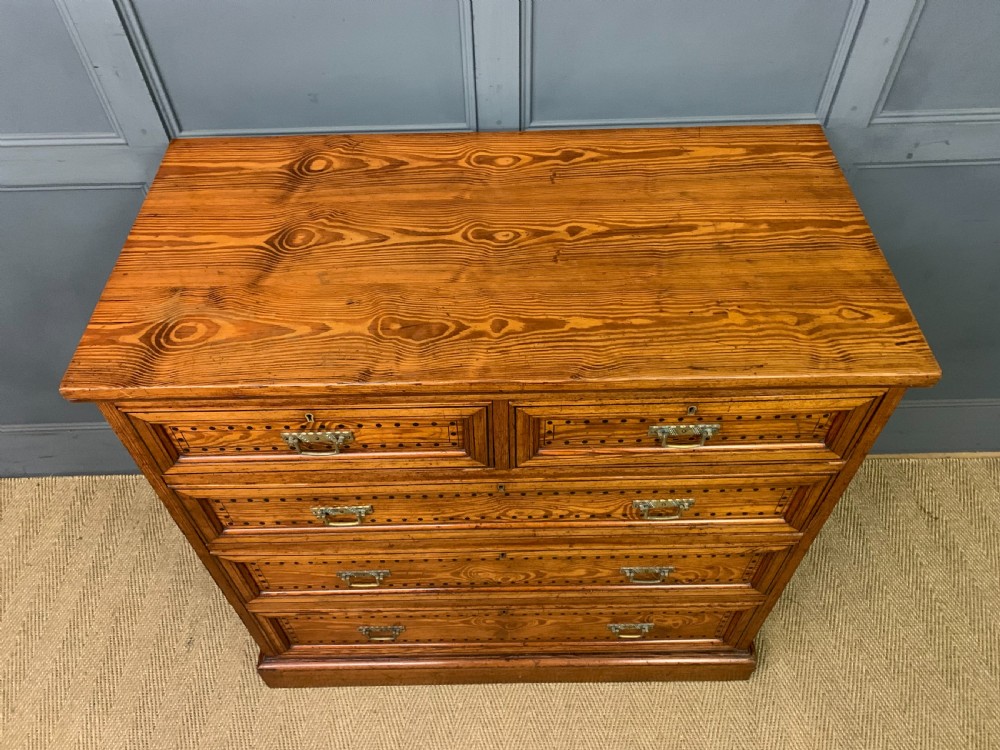 A late Victorian pitch pine chest of drawers featuring ebonised geometric dot inlay details and brass drop handles. View III