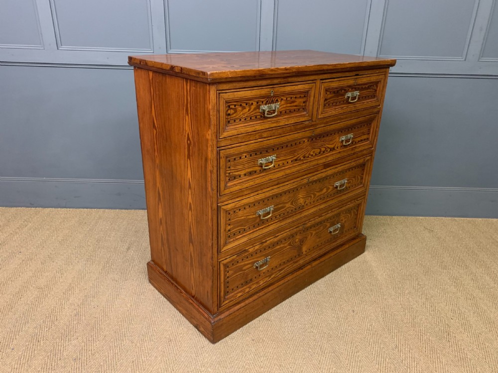 A late Victorian pitch pine chest of drawers featuring ebonised geometric dot inlay details and brass drop handles. View VIII