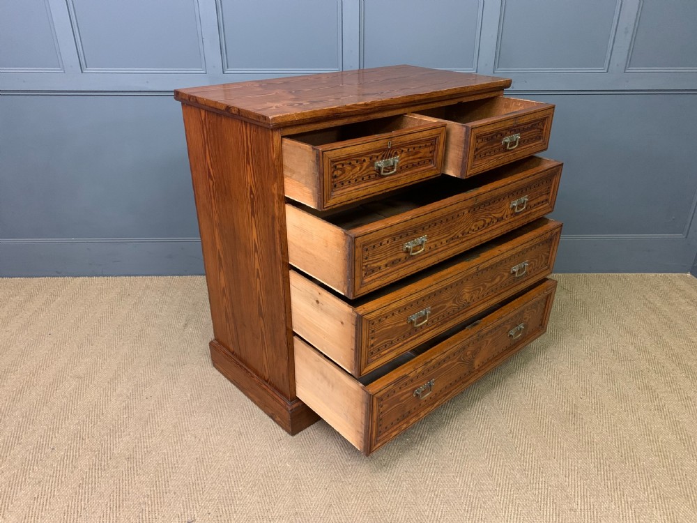 A late Victorian pitch pine chest of drawers featuring ebonised geometric dot inlay details and brass drop handles. View X