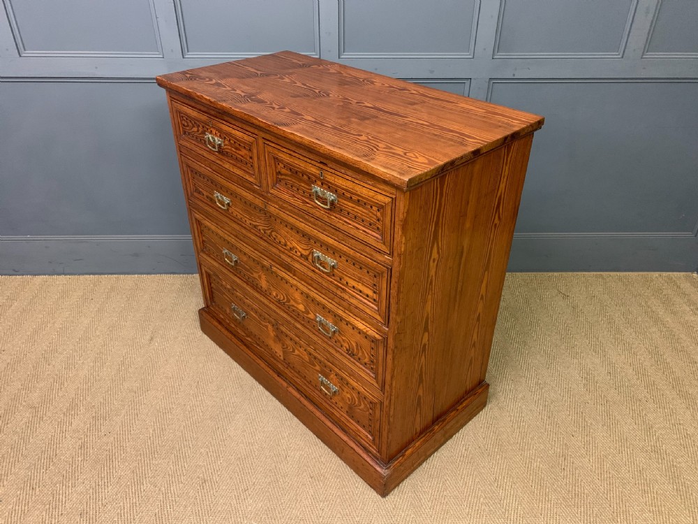 A late Victorian pitch pine chest of drawers featuring ebonised geometric dot inlay details and brass drop handles. View XI