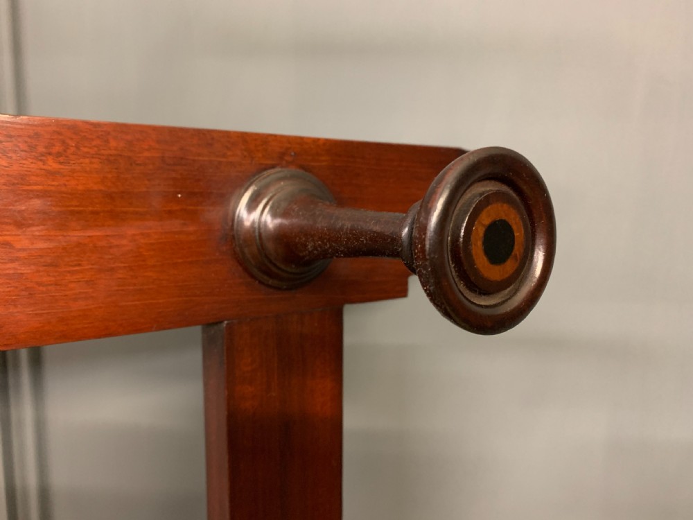 An Arts and Crafts inlaid mahogany hall stand featuring an arched central mirror, coat pegs, marble surface, and integrated umbrella racks. View XVI